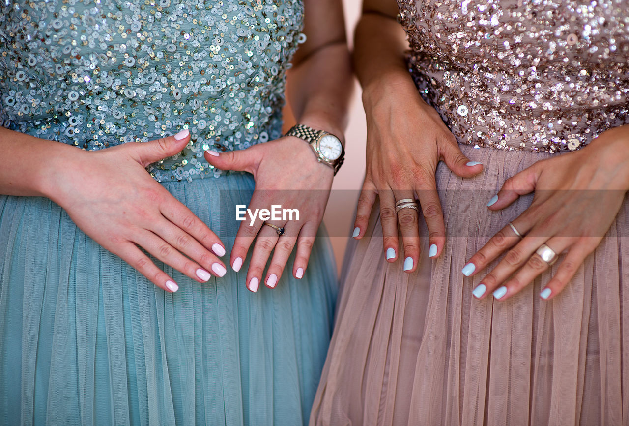 Midsection of women showing their nail polishes on fingernails