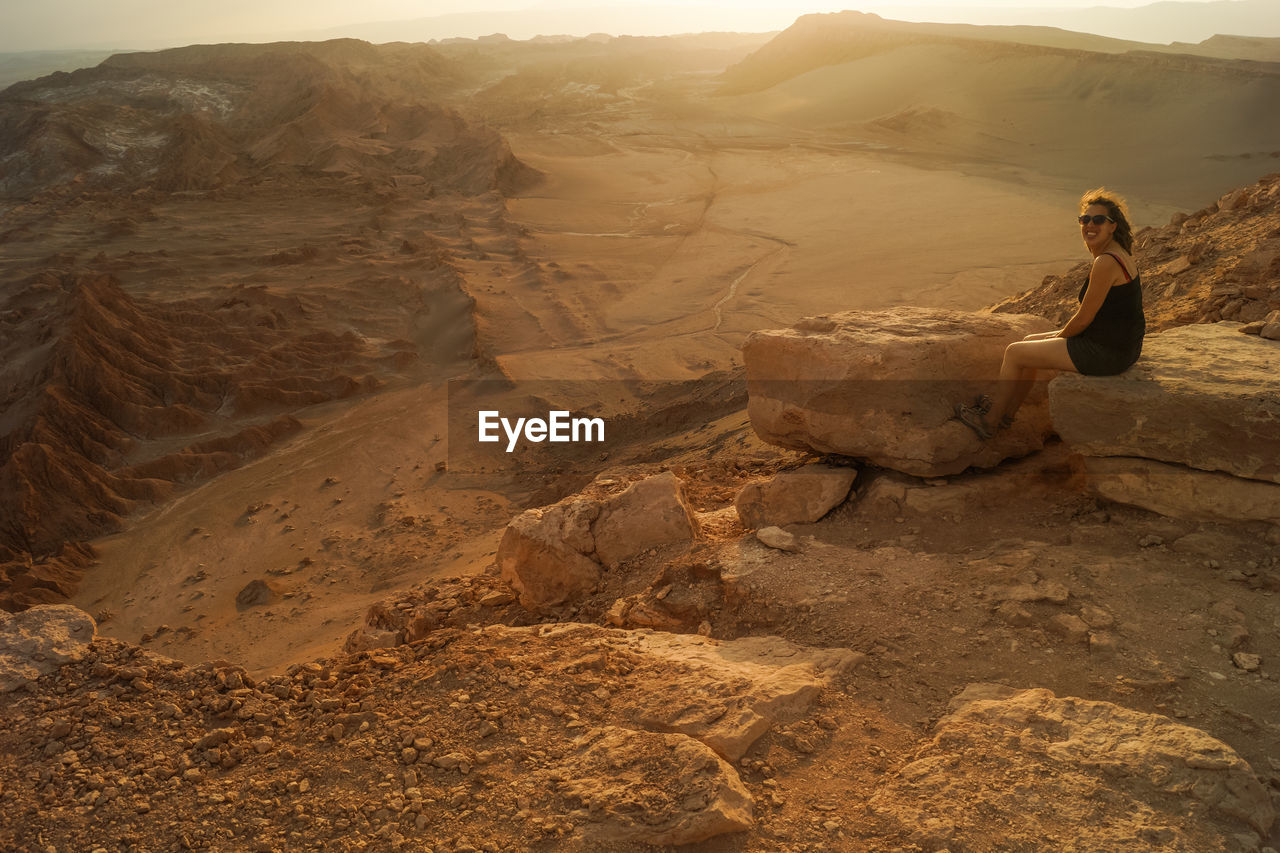 Full length of woman sitting on rock in dessert