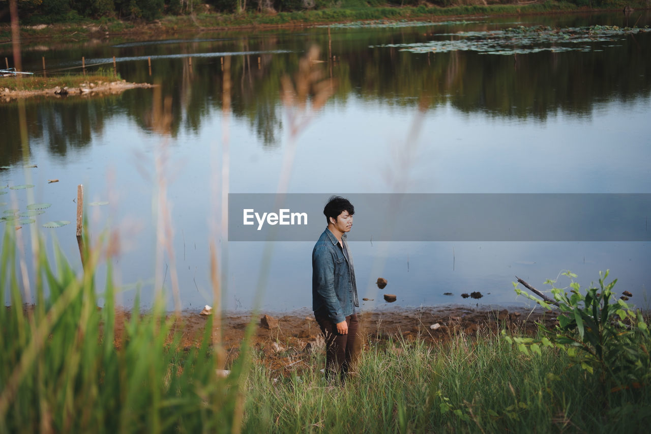 Young man standing at lake