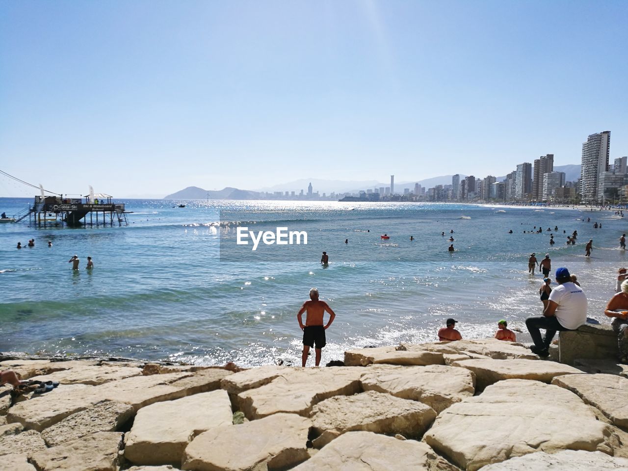 People at beach against clear sky during summer