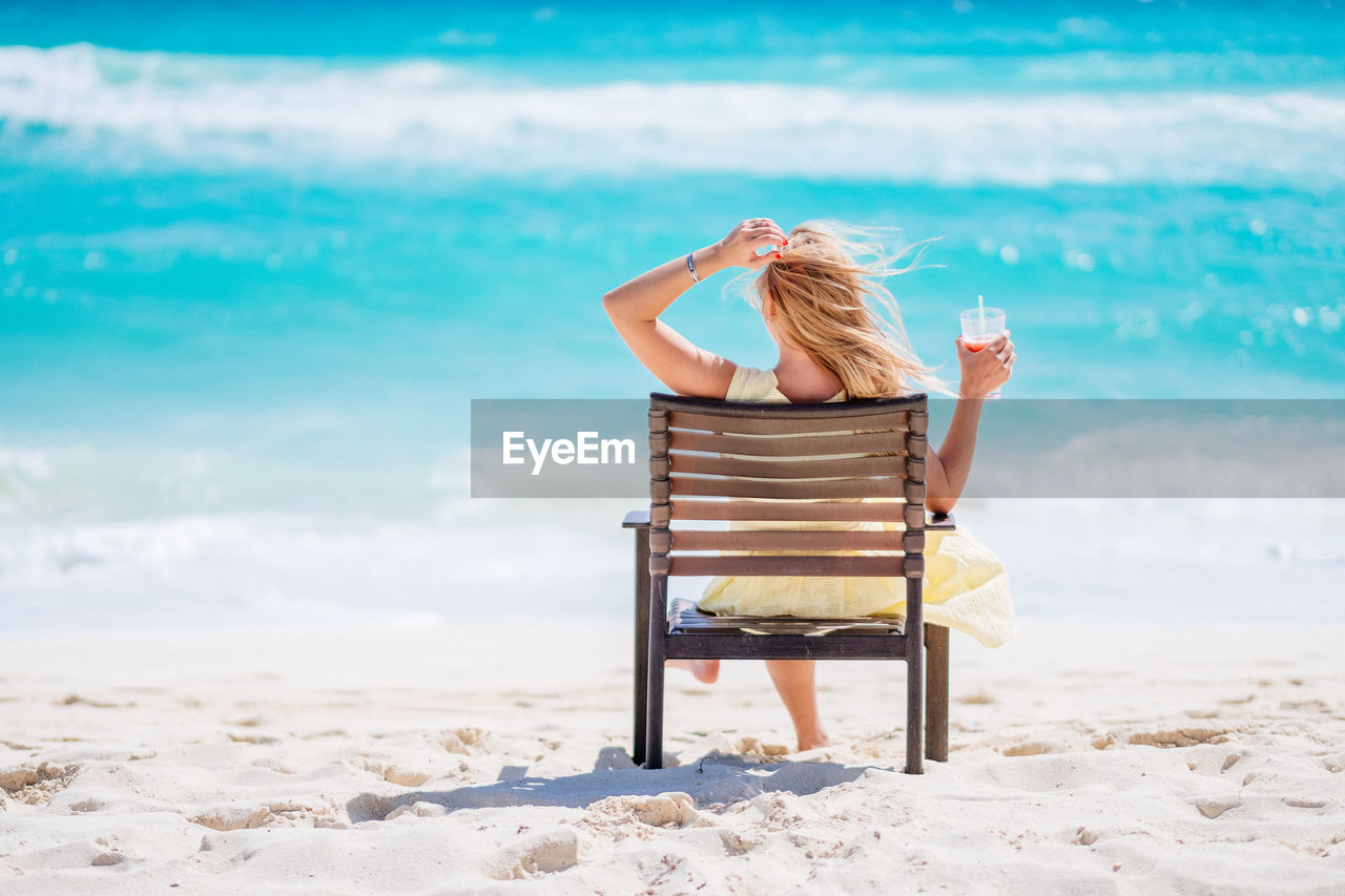 Woman sitting on beach against sea