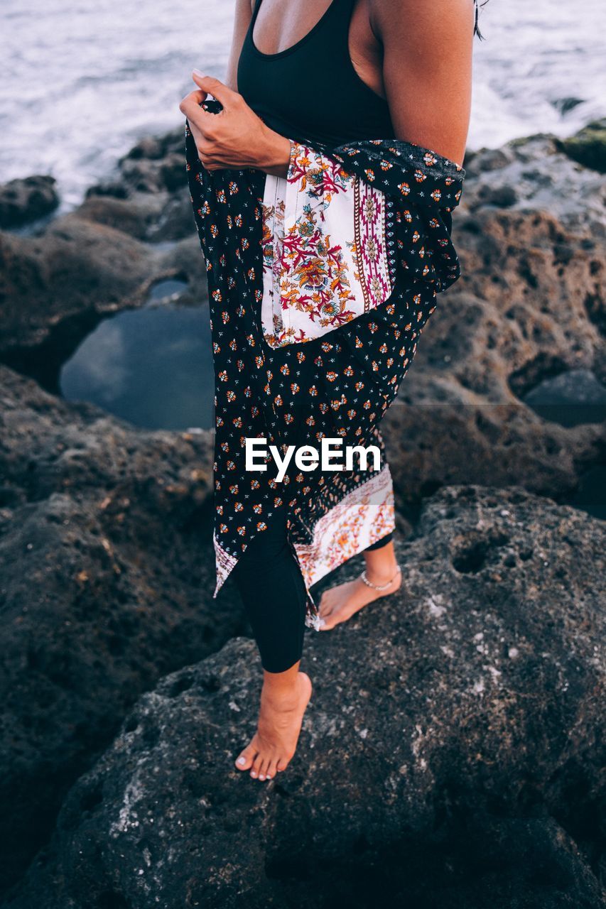 LOW SECTION OF WOMAN STANDING ON ROCKS