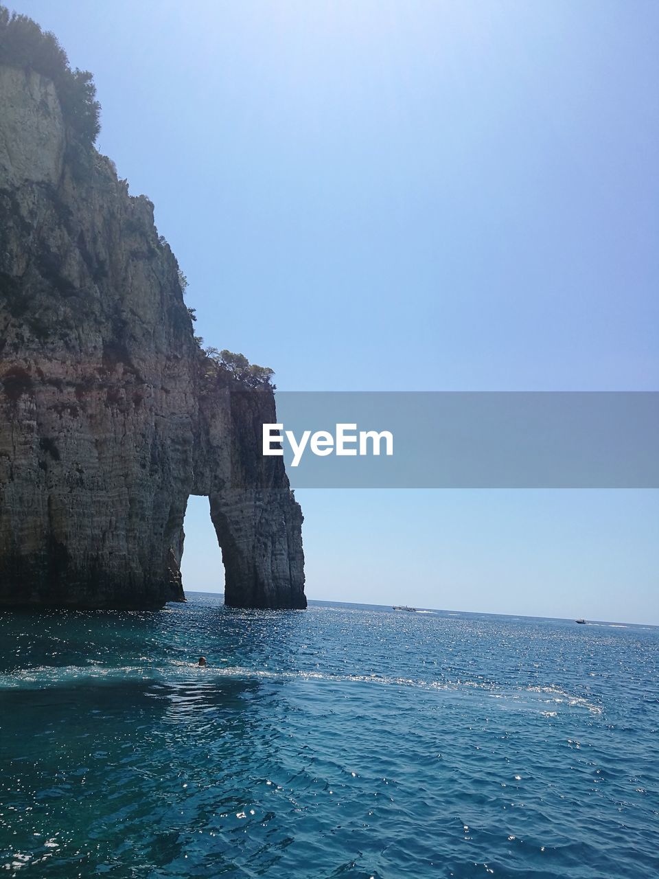 ROCK FORMATIONS IN SEA AGAINST CLEAR BLUE SKY