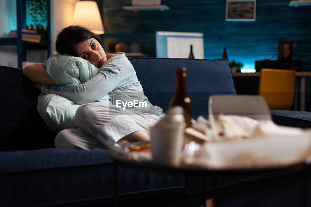 Depressed woman sitting on sofa at home