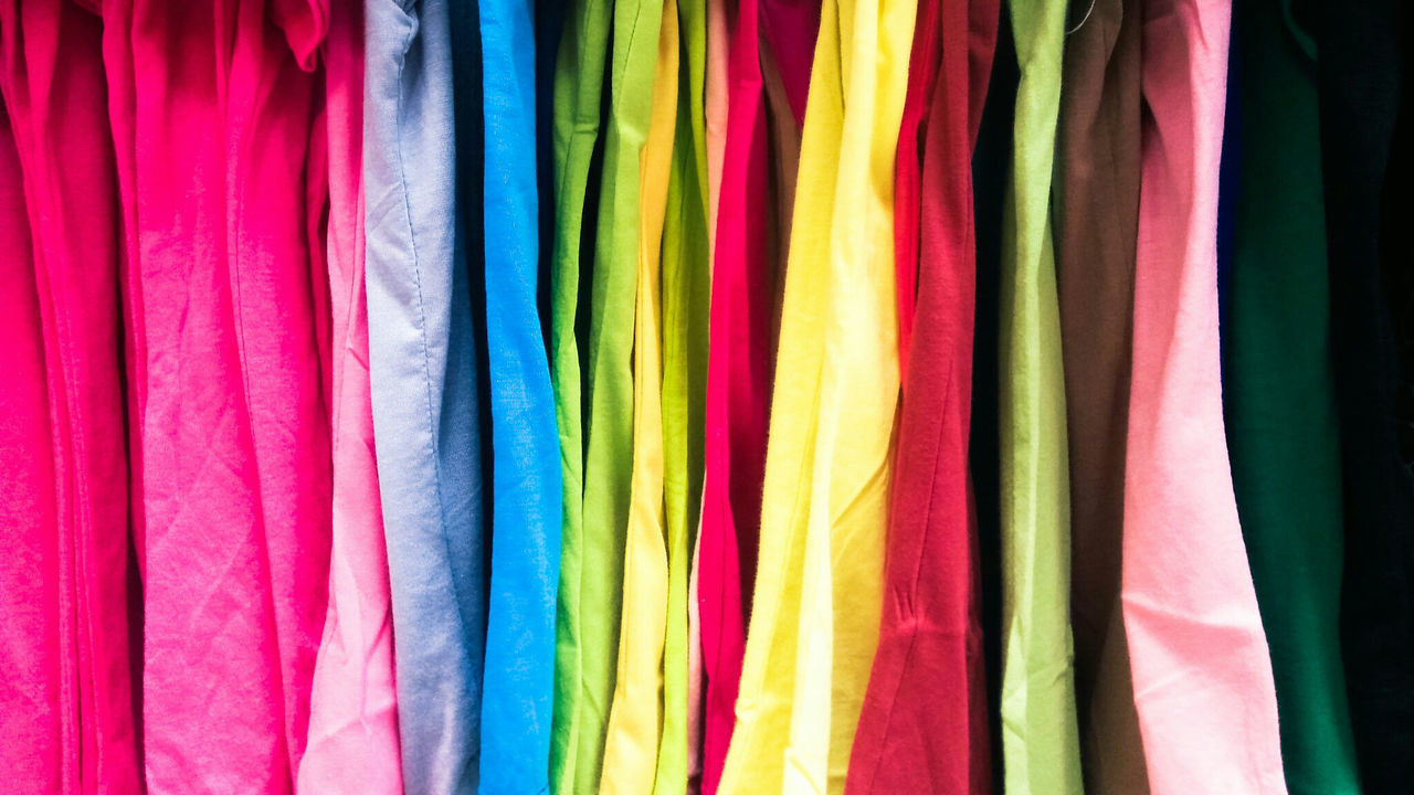 Close-up of multi colored clothes hanging at shop for sale