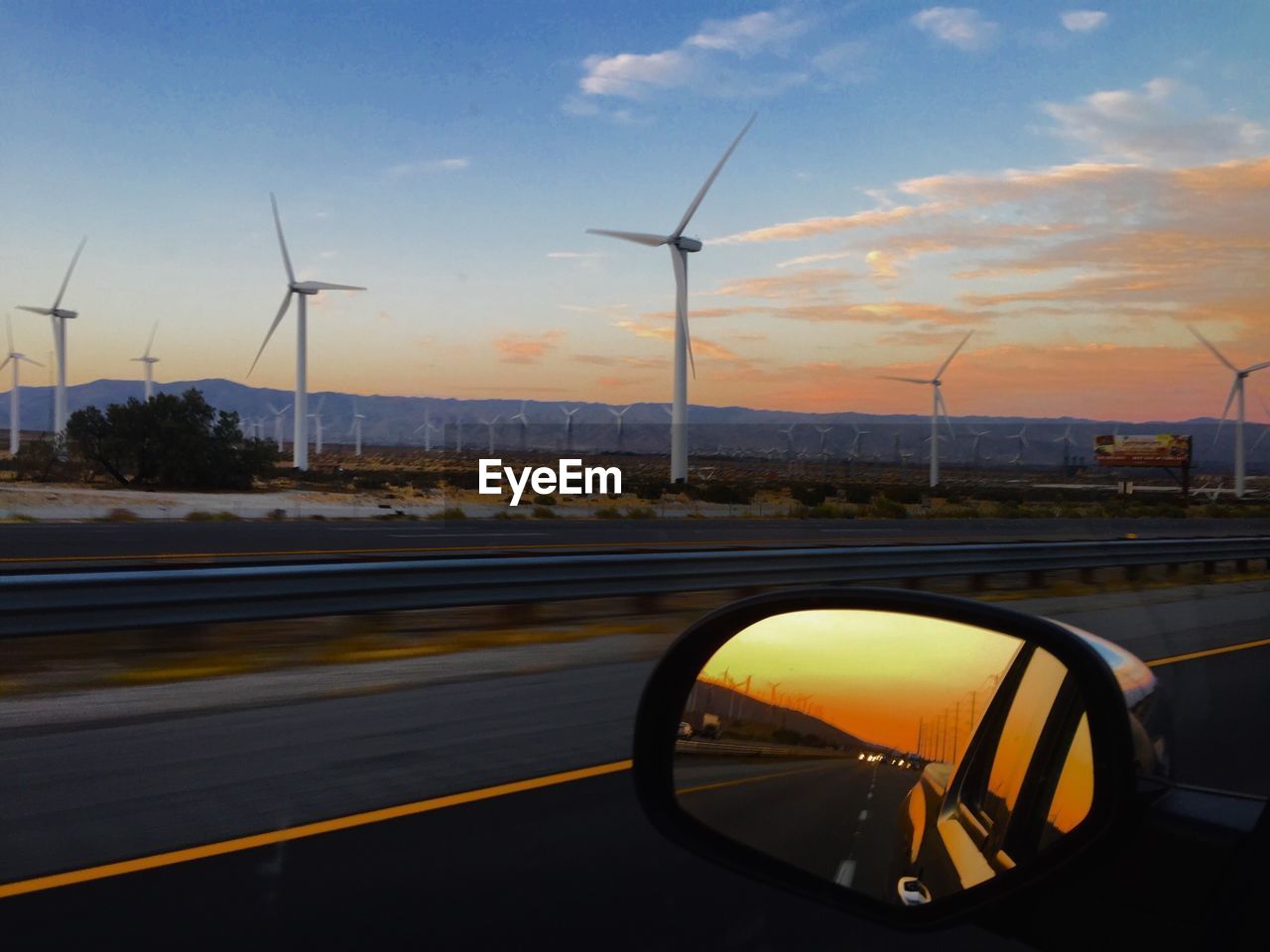 CLOSE-UP OF CAR ON ROAD AGAINST SUNSET SKY