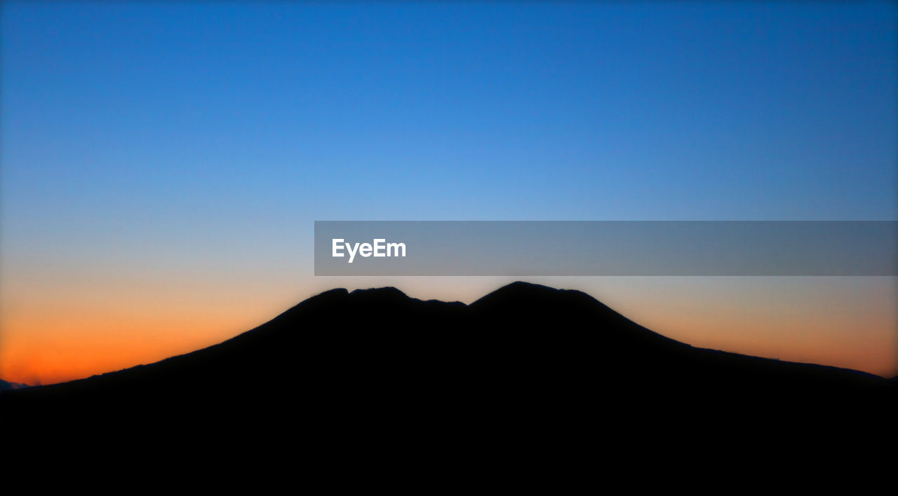 SILHOUETTE MOUNTAINS AGAINST CLEAR SKY AT SUNSET
