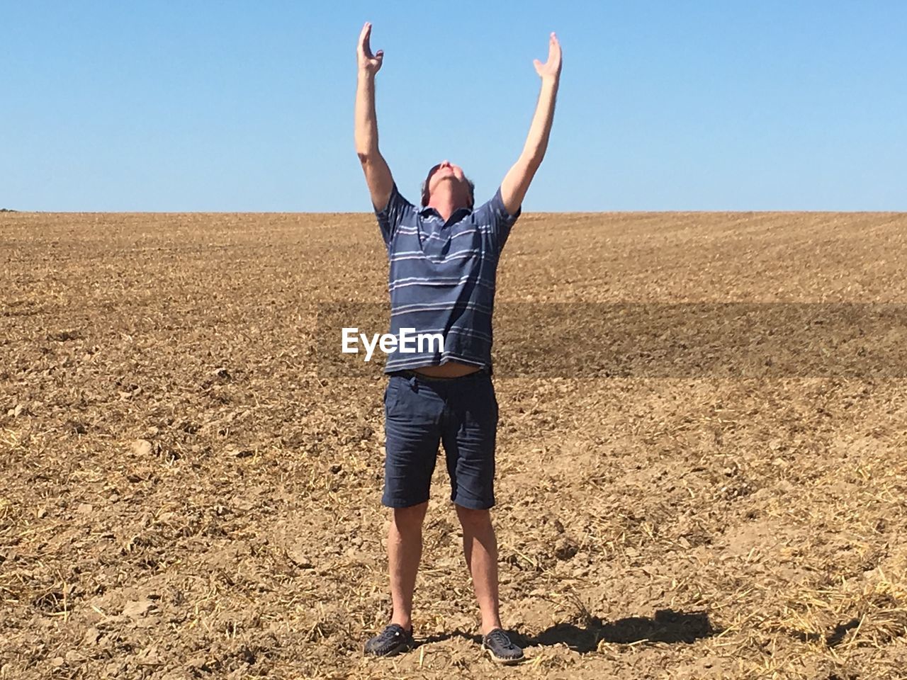 Full length of man with arms raised standing on field