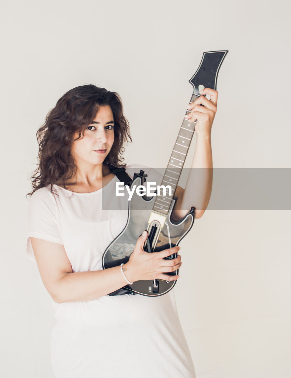Portrait of beautiful woman holding guitar against white background