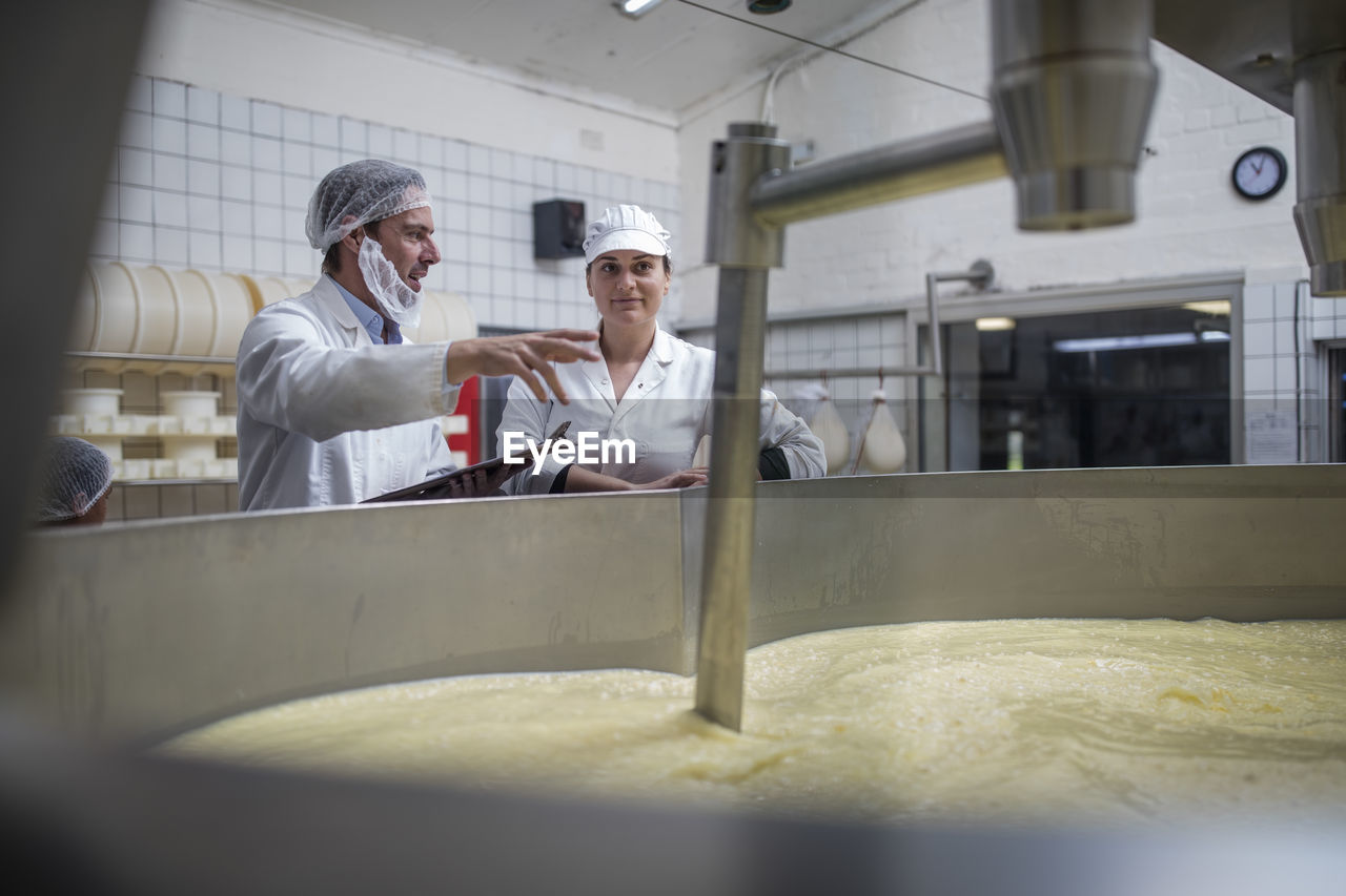 Cheese factory workers controlling curdling process