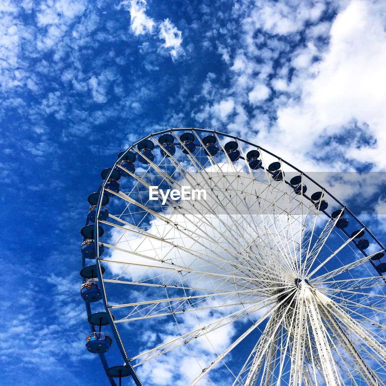 Low angle view of ferris wheel against blue sky and clouds