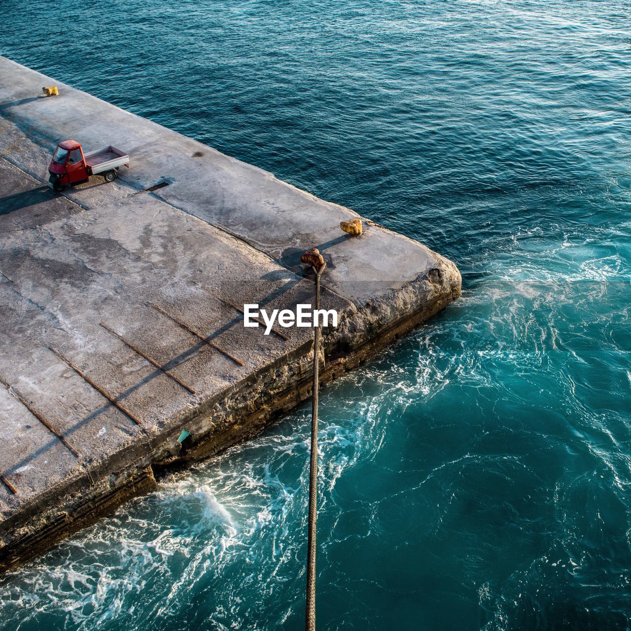 High angle view of rope tied on bollard by turquoise sea