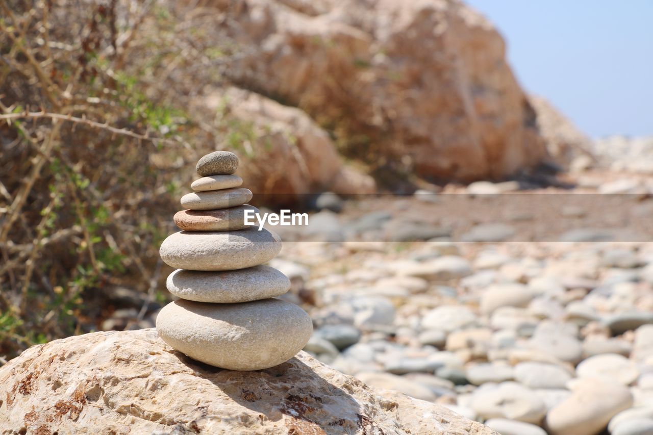 Stacked pebbles on rock at beach during sunny day