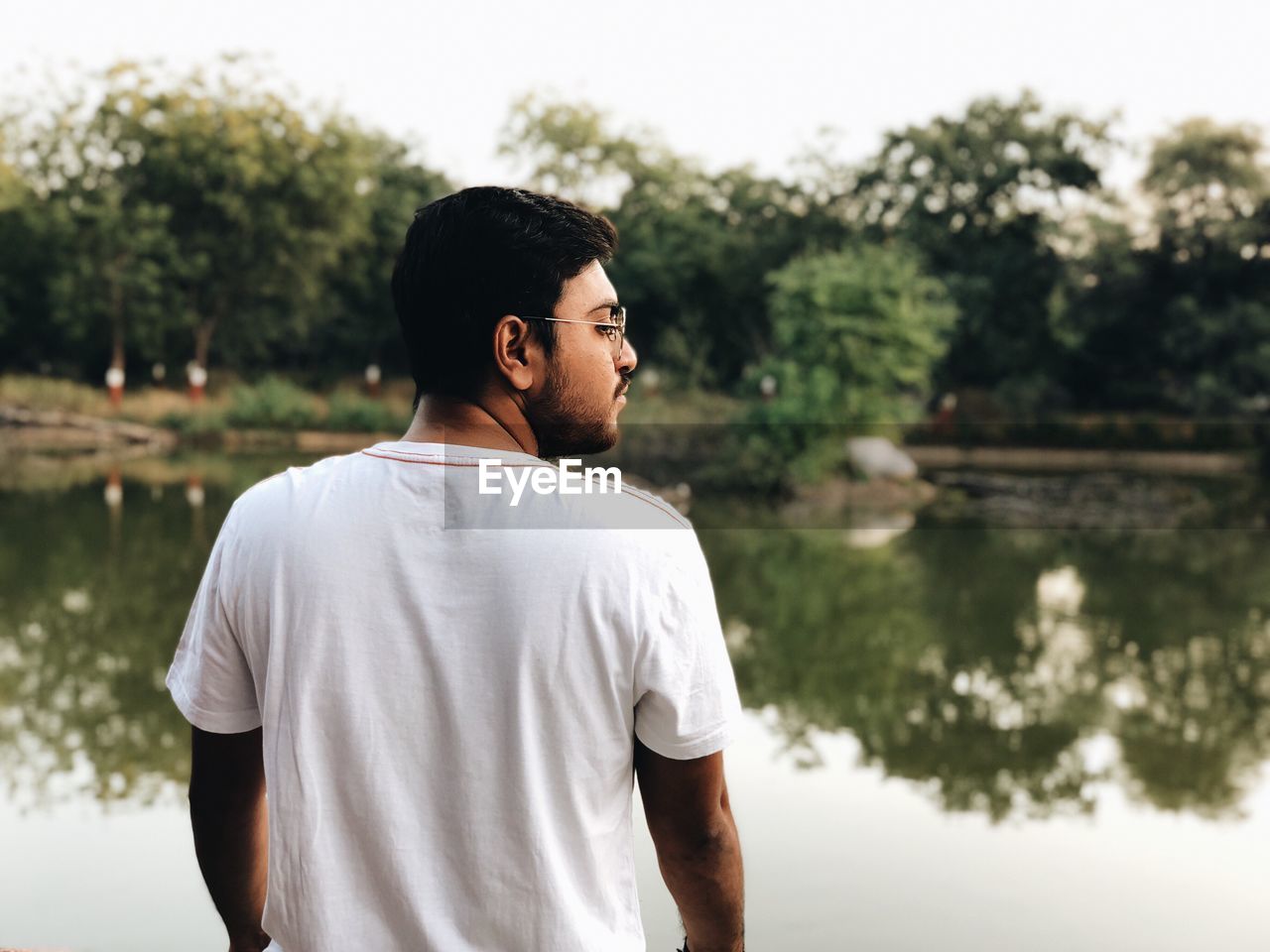 Rear view of man standing by lake