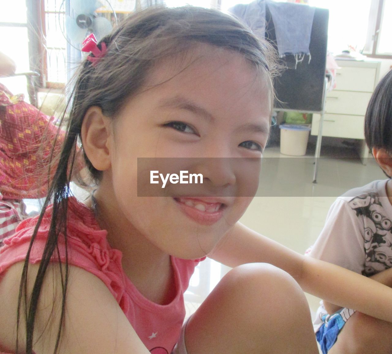 CLOSE-UP PORTRAIT OF SMILING GIRL SITTING IN OFFICE