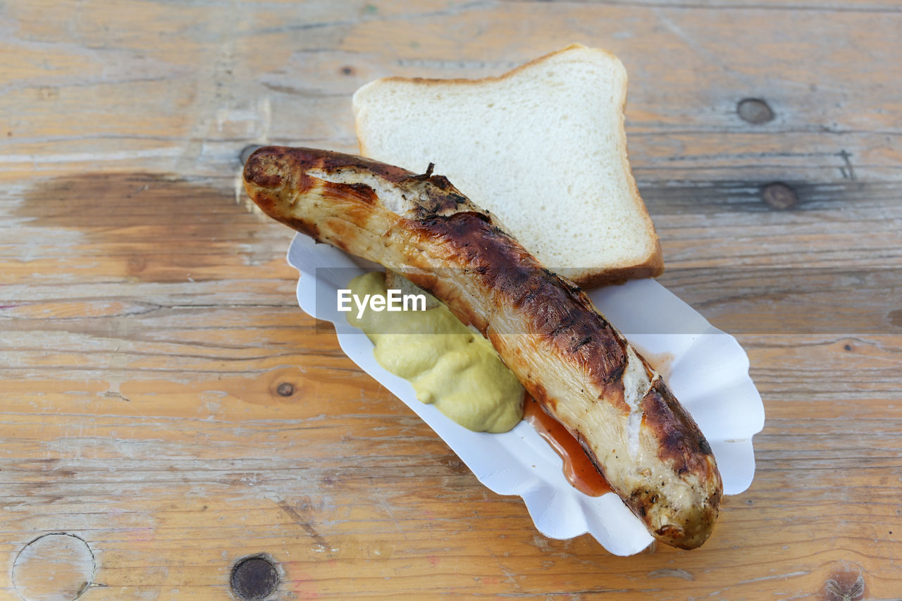 food, food and drink, fast food, wood, table, bread, freshness, bratwurst, high angle view, produce, no people, healthy eating, indoors, still life, wellbeing, directly above, dish, meat, hot dog, slice, sausage