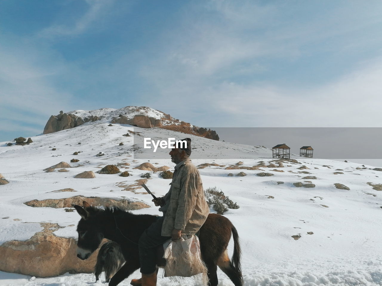 Person riding horse on snow covered mountain against sky