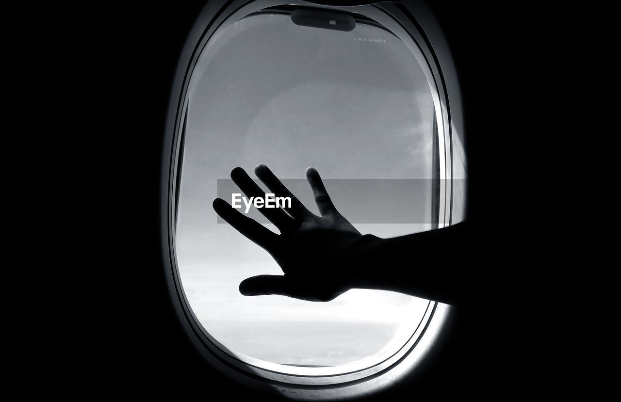 Silhouette hand touching airplane window