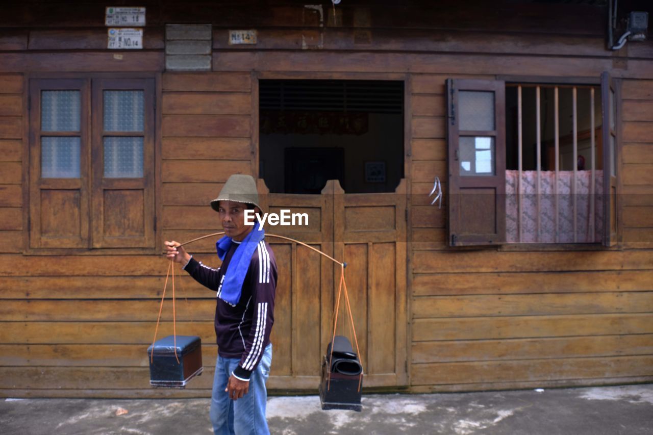 MAN STANDING AGAINST BUILDING