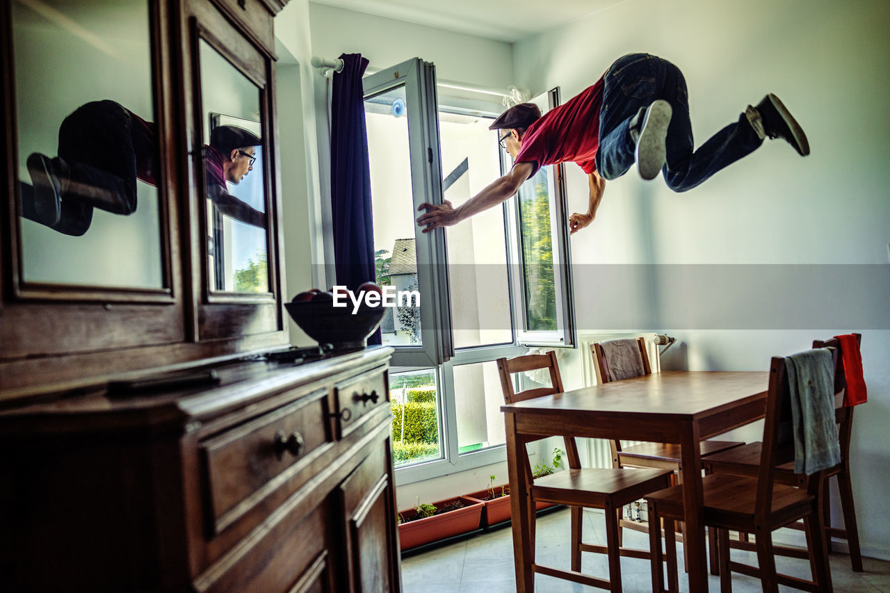 Man holding window frame while levitating at home