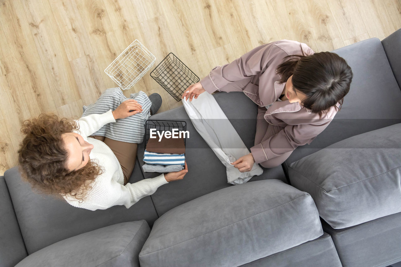 high angle view of mother and daughter using digital tablet while sitting on sofa at home