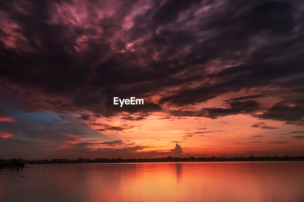 Scenic view of dramatic sky over lake during sunset