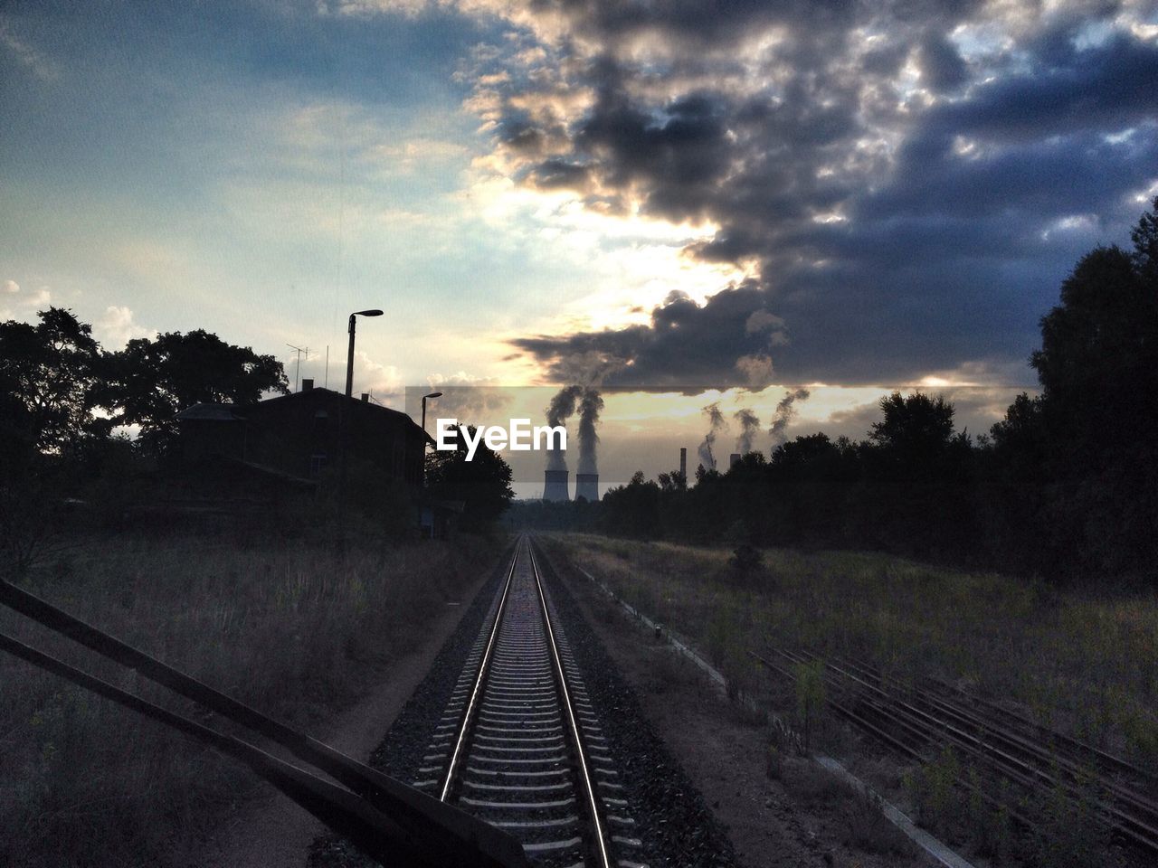 Railway track and smoke stack seen through train windshield