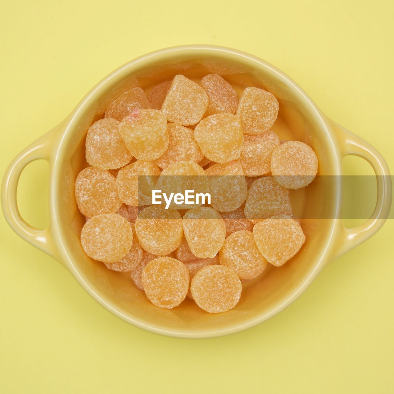 Directly above view of candies in bowl on yellow background