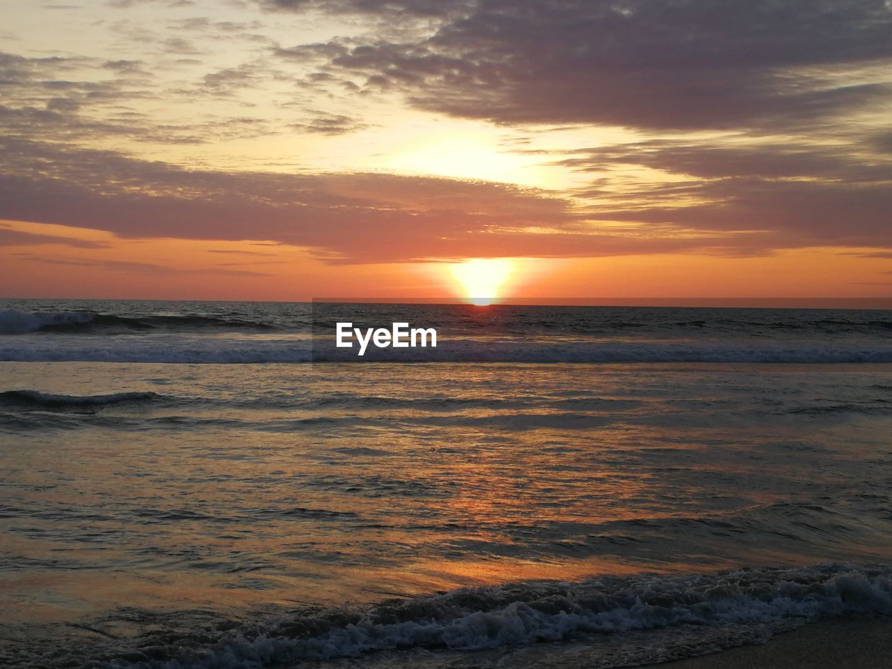 SCENIC VIEW OF SEA AGAINST CLOUDY SKY DURING SUNSET