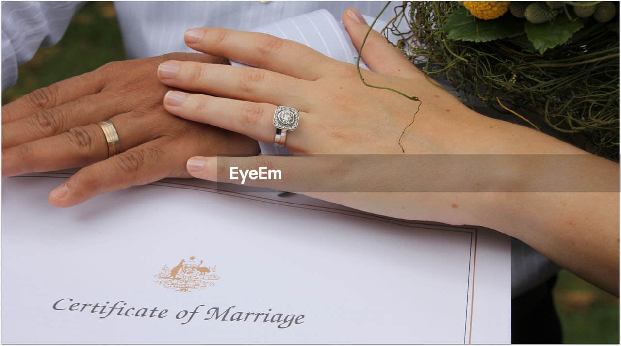 Cropped hands of wedding couple with marriage certificate