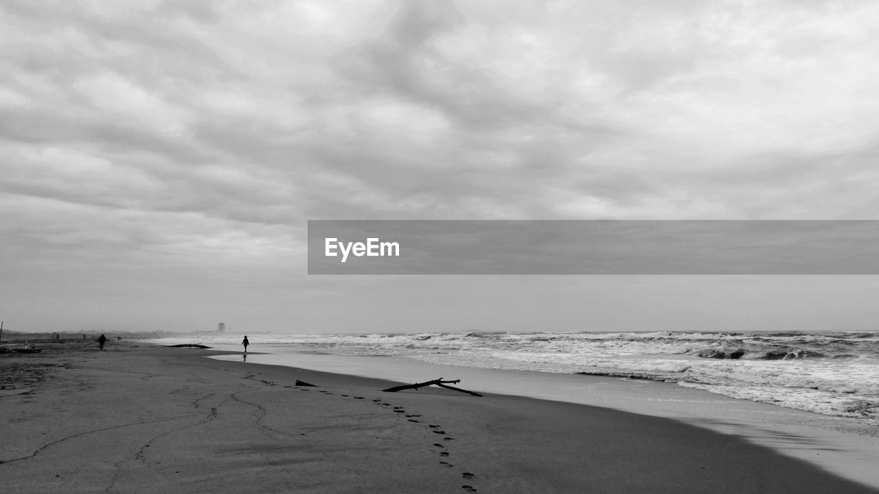 sea, beach, land, sky, water, sand, cloud, scenics - nature, black and white, beauty in nature, nature, monochrome photography, horizon, monochrome, tranquility, horizon over water, wave, environment, ocean, tranquil scene, body of water, shore, holiday, travel destinations, coast, trip, wind wave, vacation, landscape, day, travel, coastline, outdoors, tourism, non-urban scene, water's edge, no people, motion, seascape, sports, white, summer, overcast, idyllic