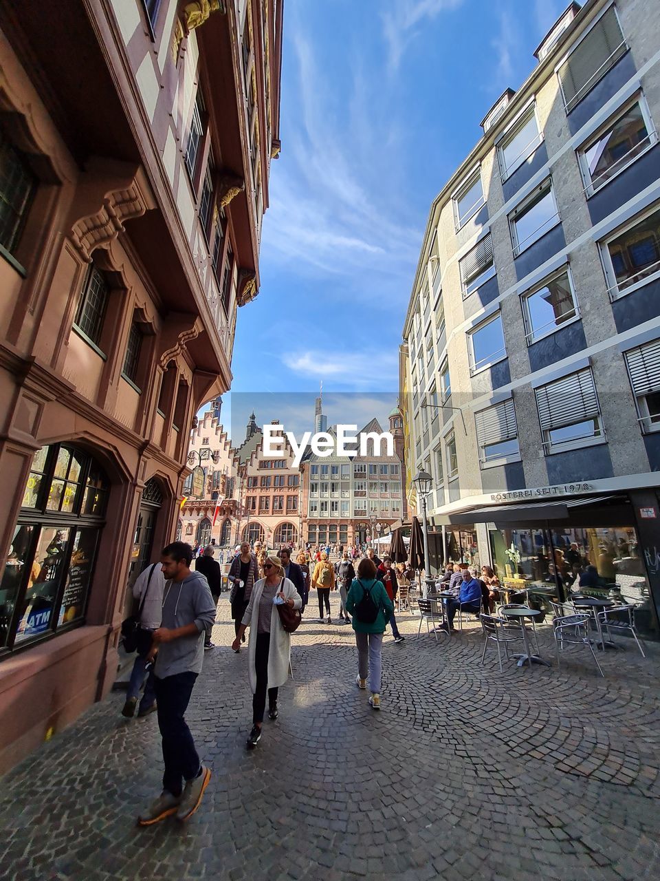 architecture, city, building exterior, built structure, street, group of people, urban area, road, town, sky, neighbourhood, building, city life, walking, adult, cityscape, downtown, travel destinations, town square, women, crowd, tourism, city street, men, large group of people, nature, travel, plaza, cobblestone, infrastructure, lifestyles, tourist, residential district, business, day, walkway, outdoors, landmark, cloud, person