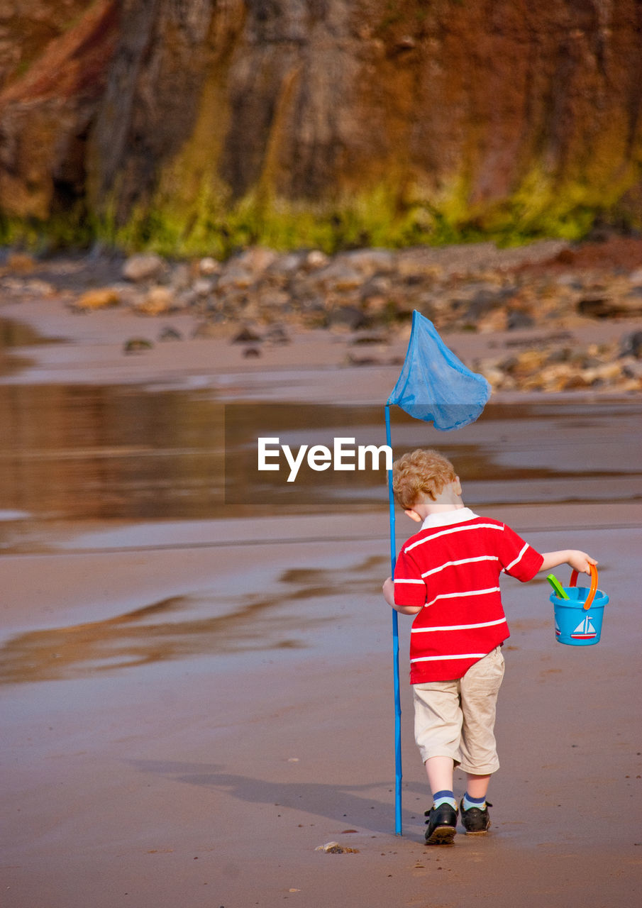 Boy with fishing net walking at beach