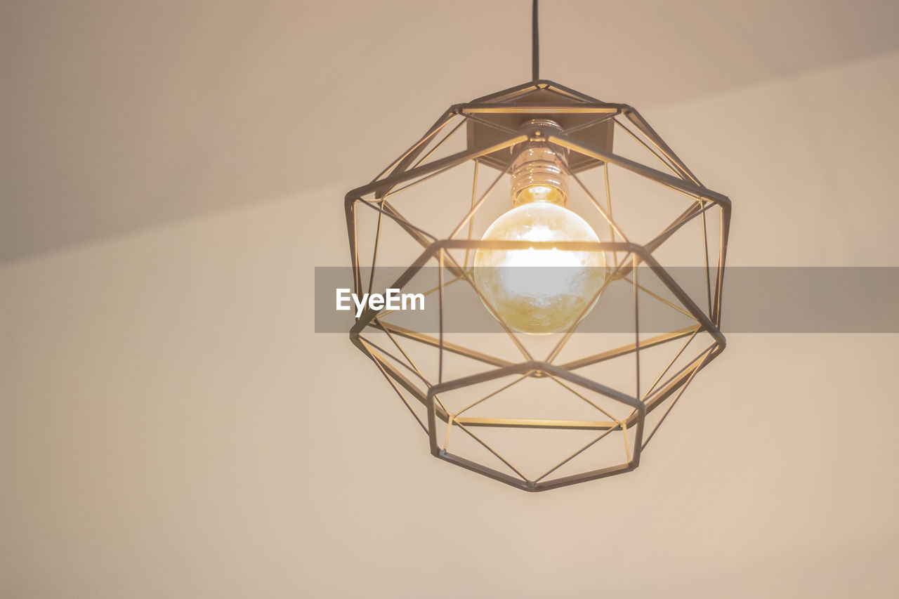 Close-up of illuminated light bulb hanging on ceiling