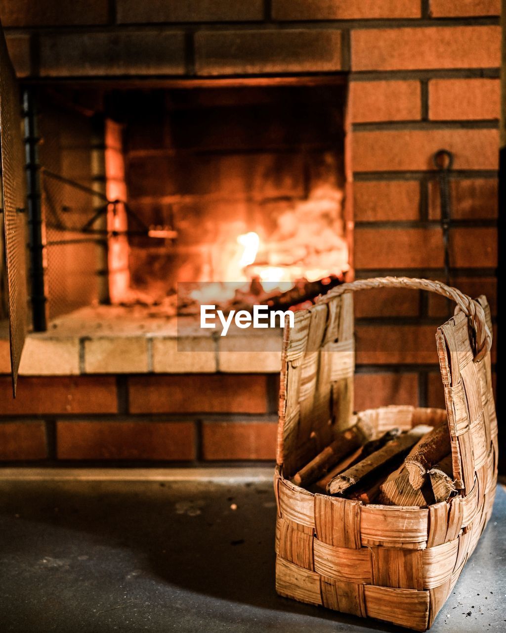 Firewood in wicker basket on table against fireplace at home