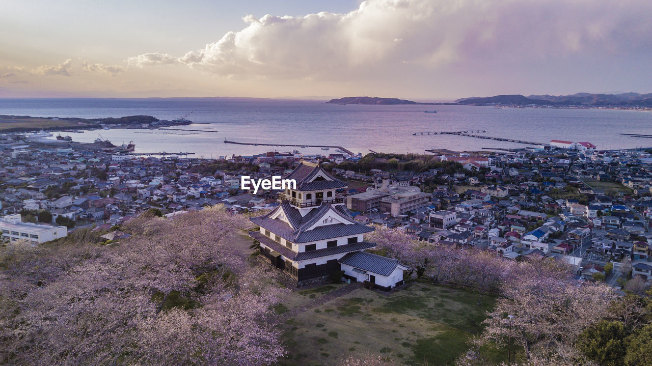 HIGH ANGLE VIEW OF TOWNSCAPE AND SEA AGAINST SKY