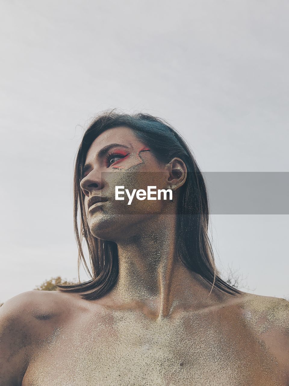 Portrait of young woman looking away against sky