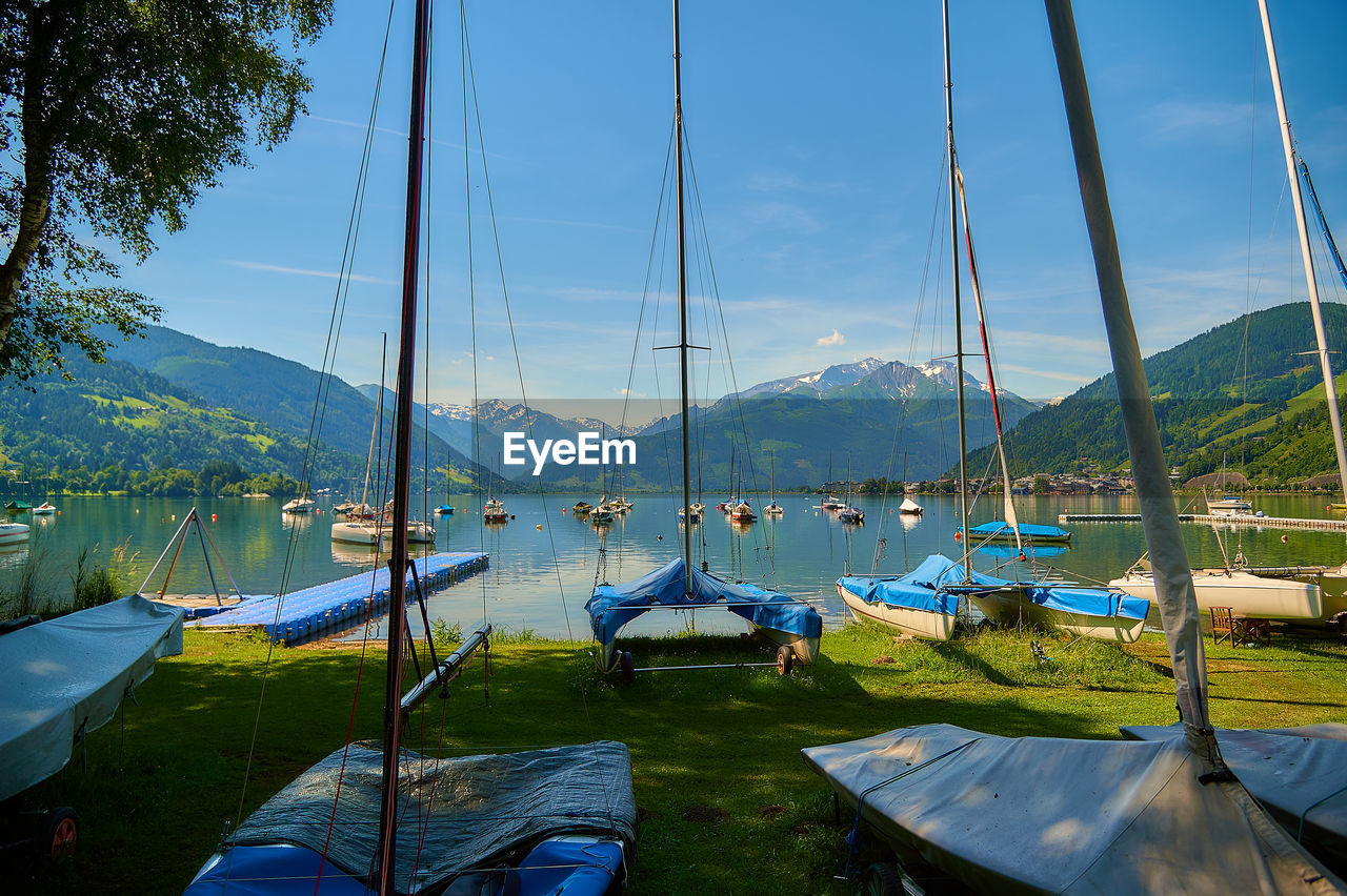 SAILBOATS MOORED AT LAKE AGAINST SKY