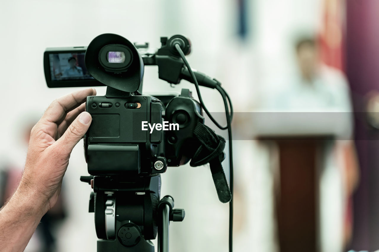 Cropped hand video recording speaker standing on stage