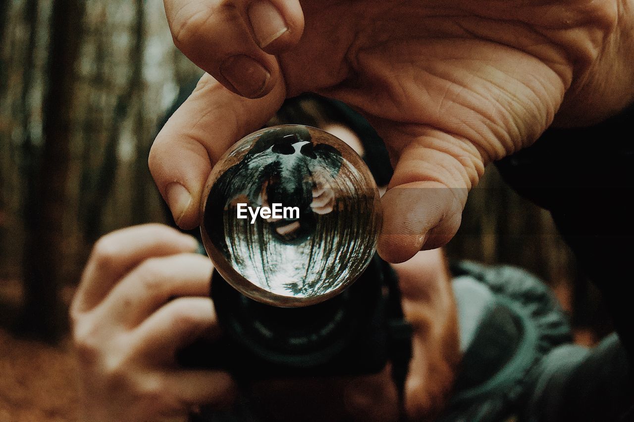 Cropped hand of person holding crystal ball and camera