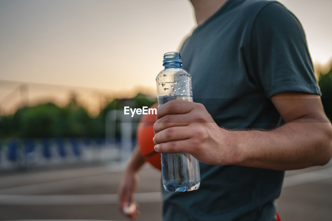 midsection of man drinking water bottle