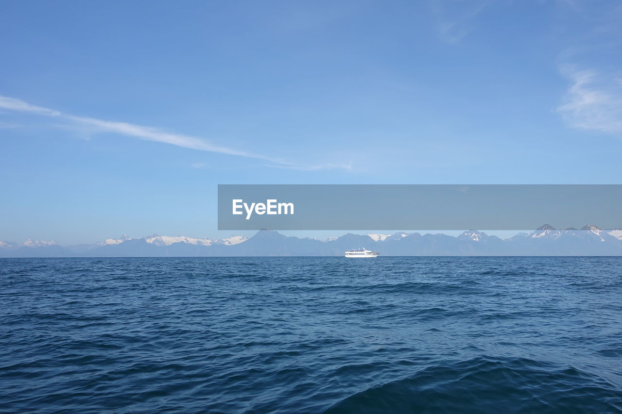 SCENIC VIEW OF SEA BY MOUNTAIN AGAINST BLUE SKY