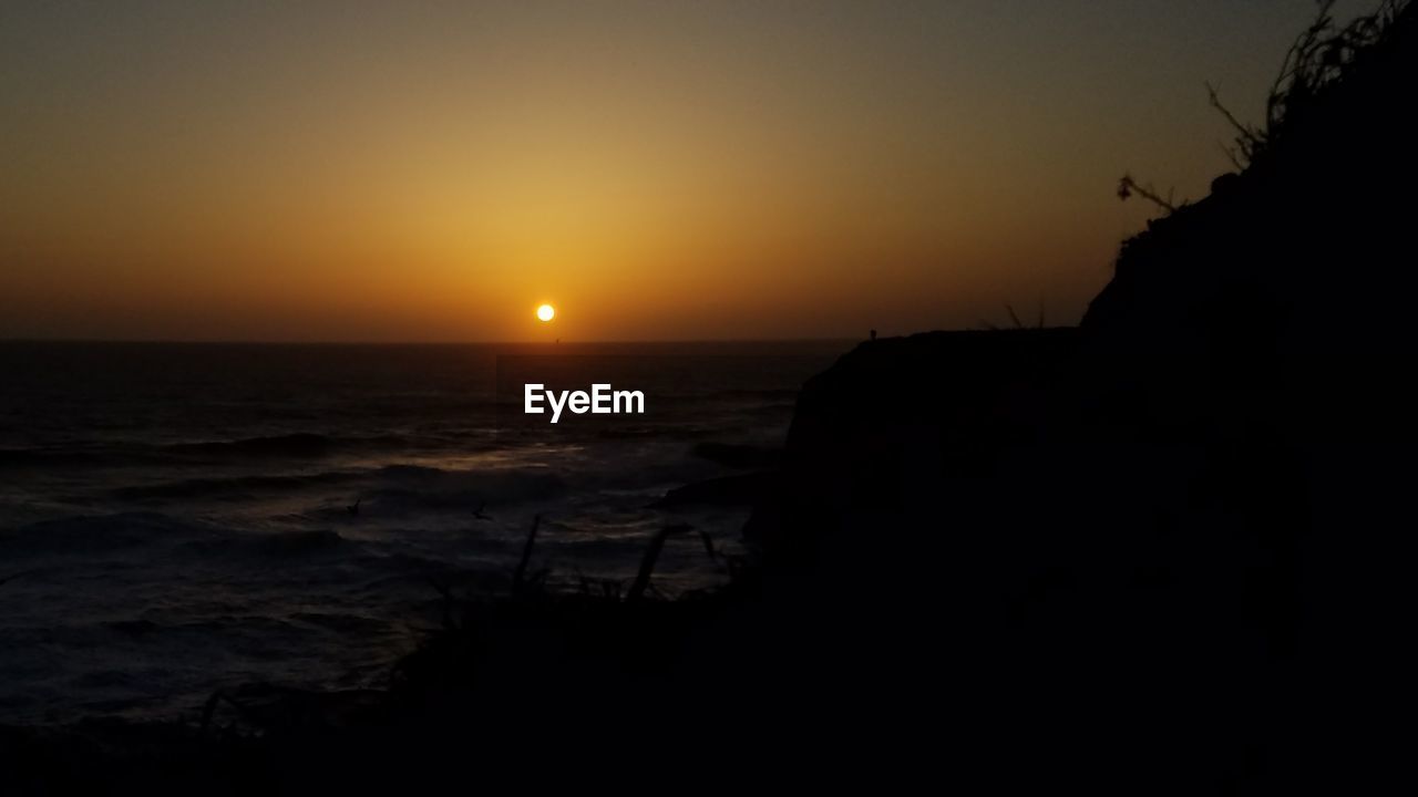 SCENIC VIEW OF SEA AGAINST ORANGE SKY