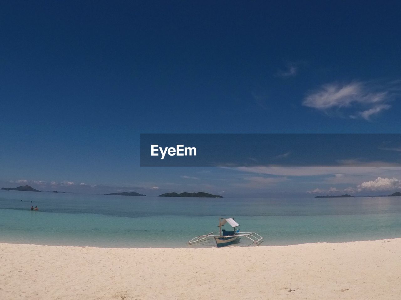 Outrigger on beach against blue sky