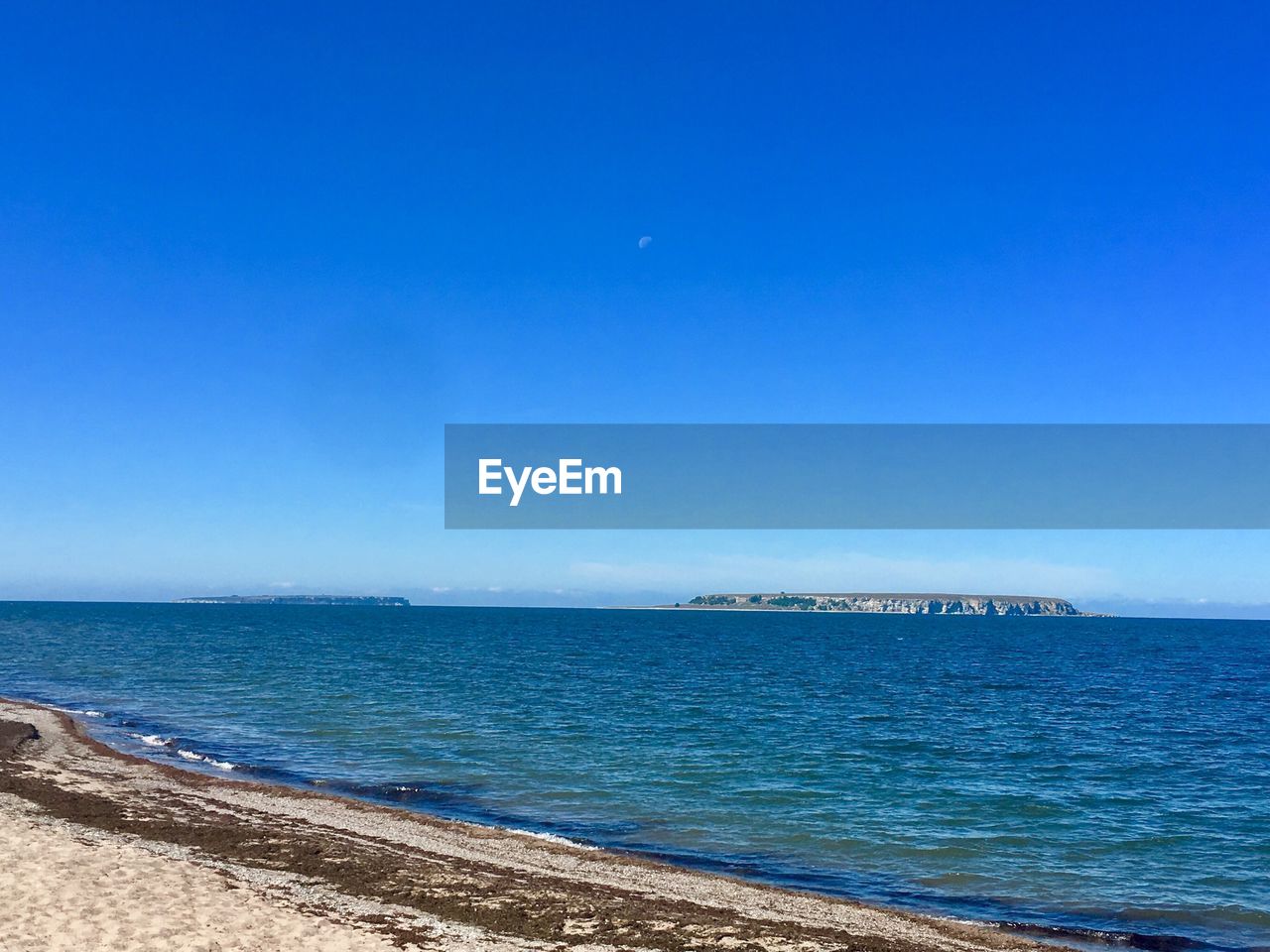 Scenic view of sea against clear blue sky