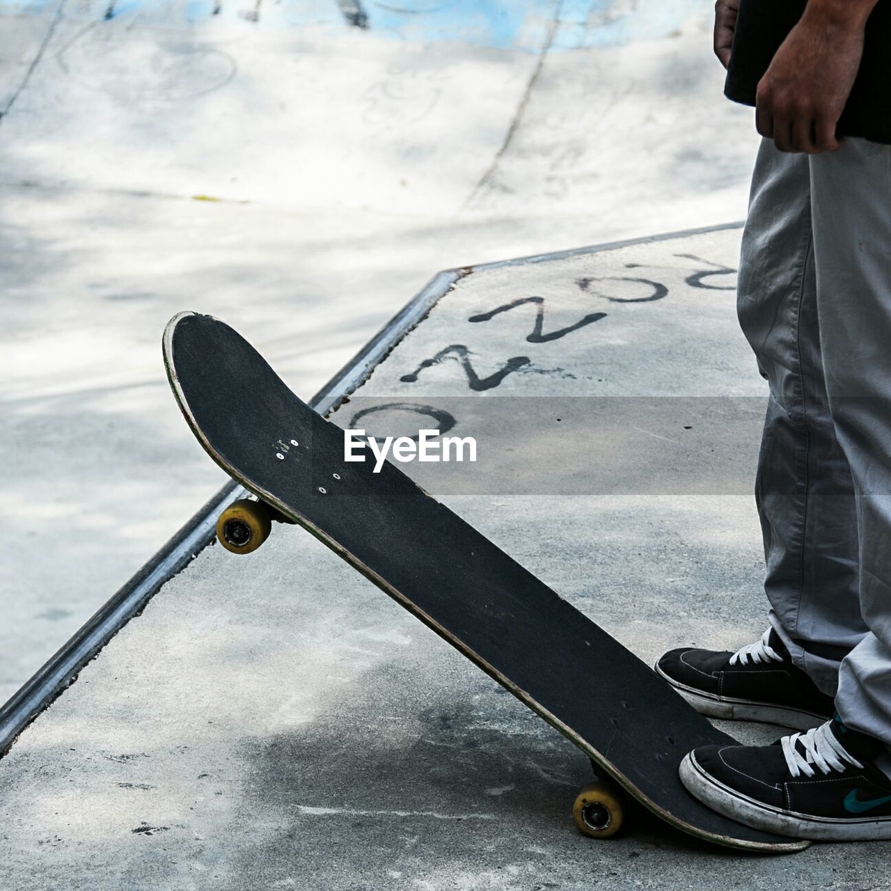 Low section of man with skateboard standing on street