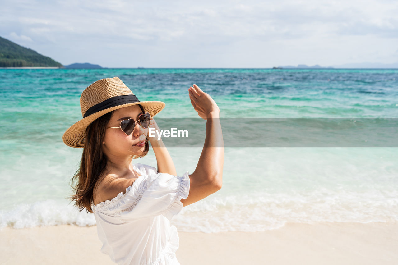 YOUNG WOMAN IN SUNGLASSES ON BEACH