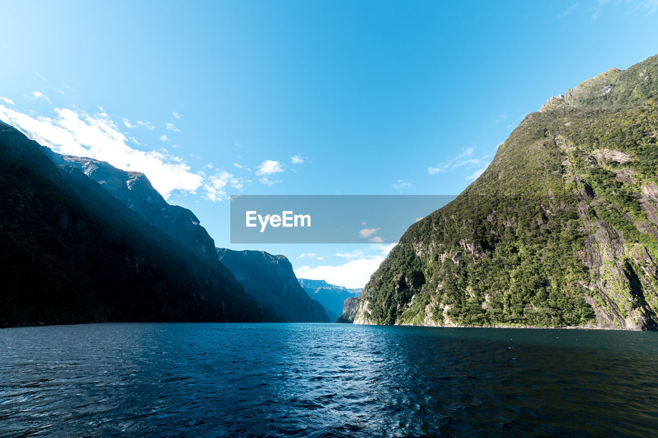 Scenic view of sea by mountains against sky