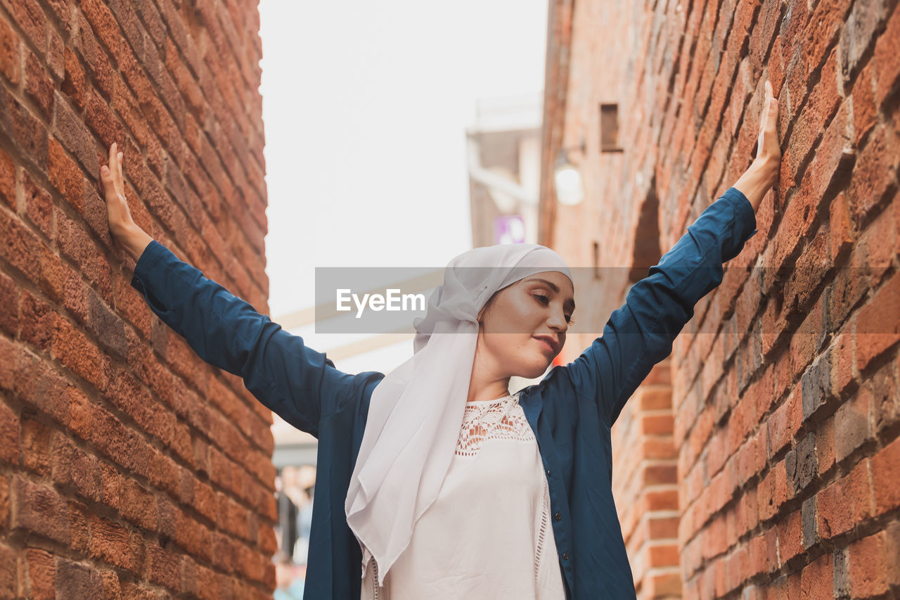 Young woman standing amidst brick walls