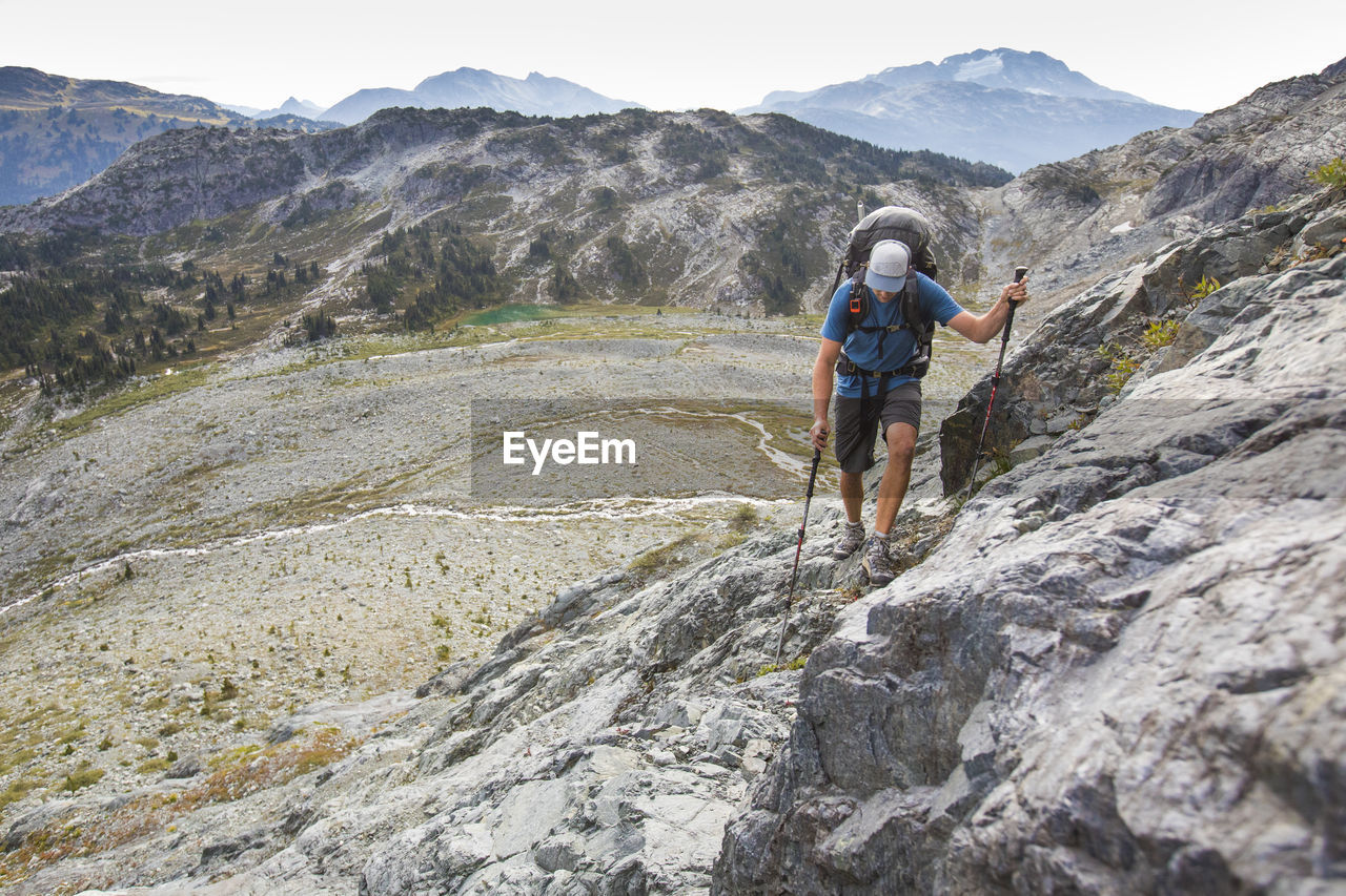 Backpacker hikes across talus slope in mountains near whistler.